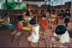 Foto da turma de alfabetizao do professor Arautar, acompanhamento pedaggico na escola Karib, comunidade Kuikuro, Parque Indgena do Xingu.  "As escolas indgenas, assim como aquelas dos no-ndios, tambm so um espao de aprendizado das crianas. Muitas vezes o contedo que  ensinado ali pelos professores  bem diferente daquele que  transmitido pelos parentes na aldeia.  claro que estes contedos podem se misturar em alguns momentos, mas a escola tem como foco ensinar a escrever, ler, fazer conta, entre outros conhecimentos importantes para o dilogo com o mundo dos no-ndios, j os parentes ensinam as formas de se organizar da comunidade, como produzir artefatos e tudo aquilo que  importante para se viver bem naquele grupo."